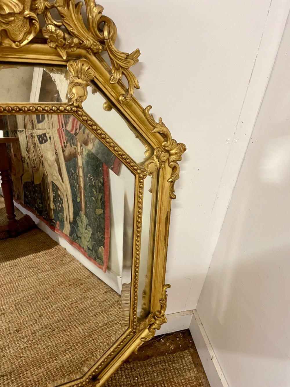 An ornate Napoleon III gilt cushion framed wall mirror with bevelled glass and carved scrollwork details. View VI