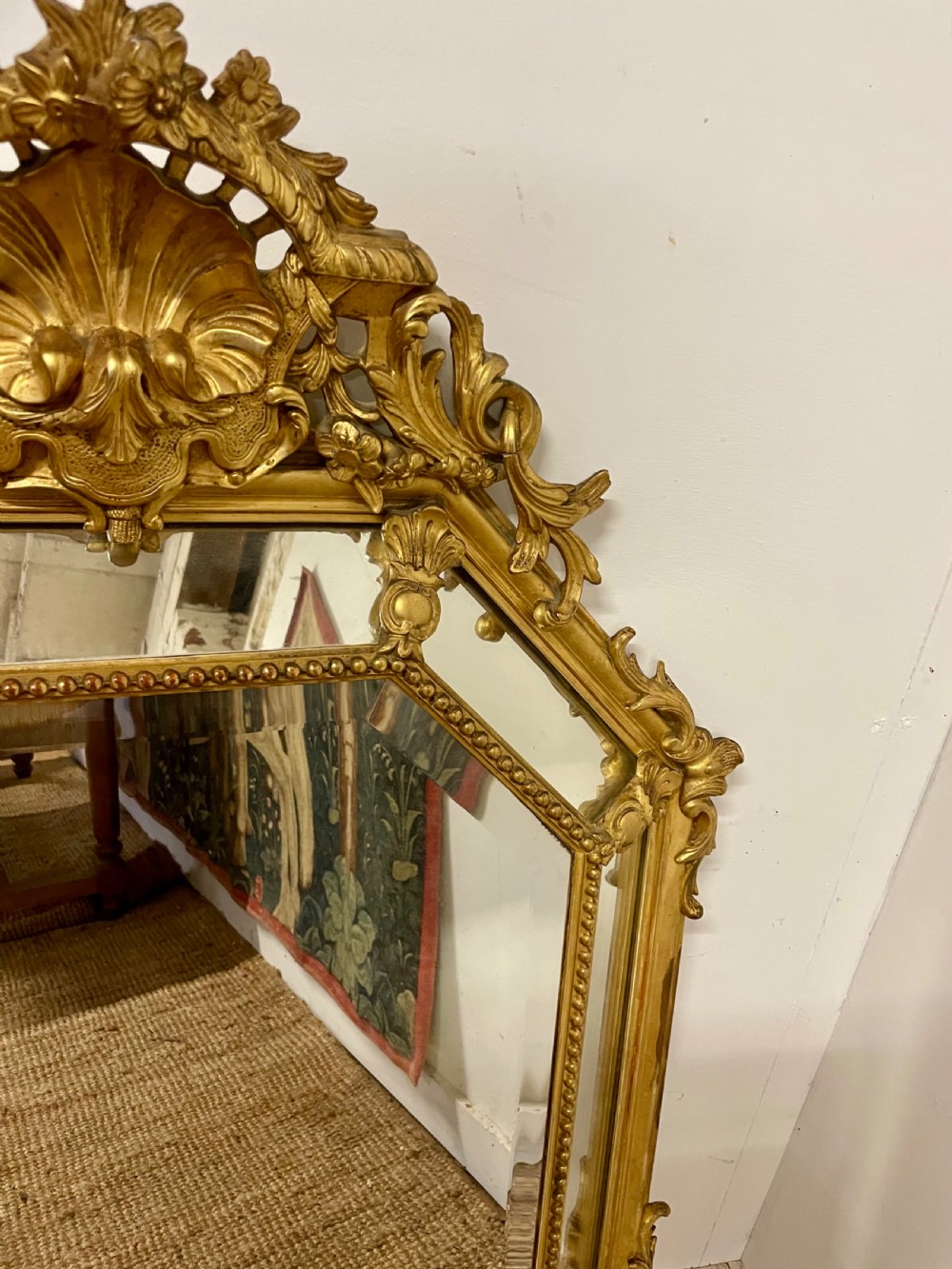 An ornate Napoleon III gilt cushion framed wall mirror with bevelled glass and carved scrollwork details. View VII