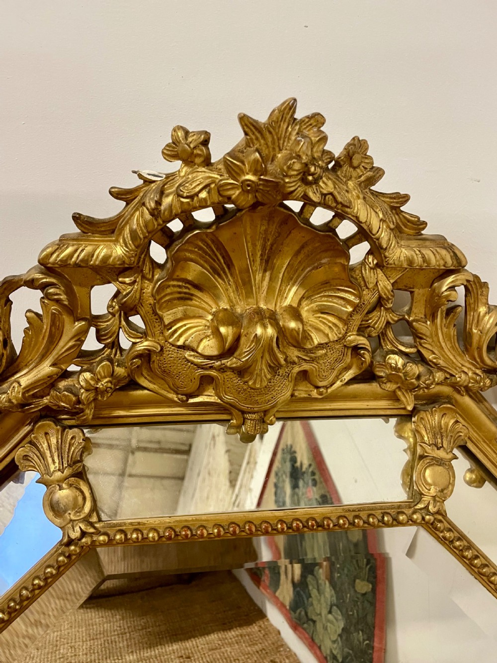 An ornate Napoleon III gilt cushion framed wall mirror with bevelled glass and carved scrollwork details. View VIII