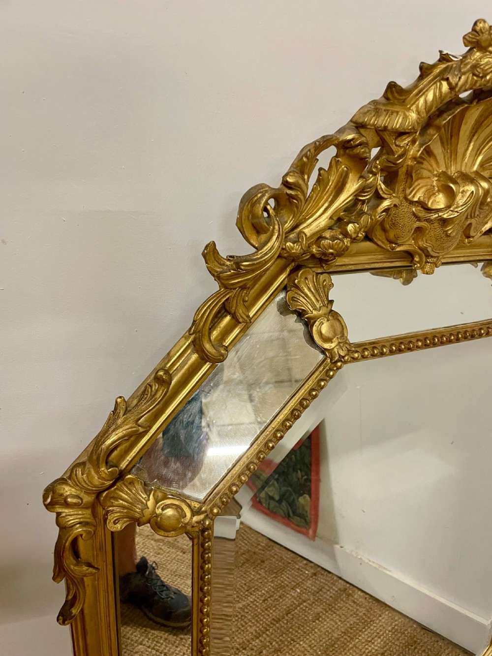 An ornate Napoleon III gilt cushion framed wall mirror with bevelled glass and carved scrollwork details. View IX