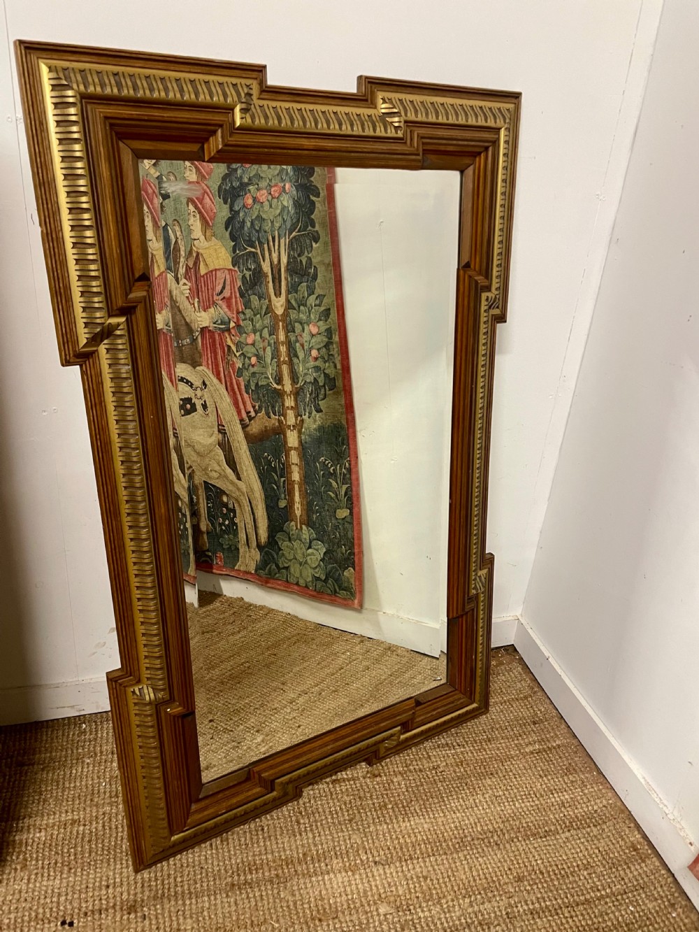 A rectangular walnut wall mirror featuring stepped architectural corner mouldings and carved parcel gilt accent trim.