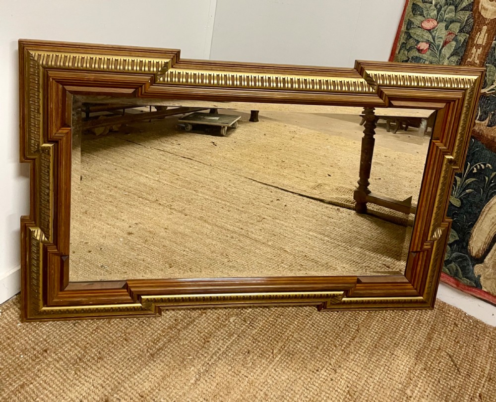 A rectangular walnut wall mirror featuring stepped architectural corner mouldings and carved parcel gilt accent trim. View IX