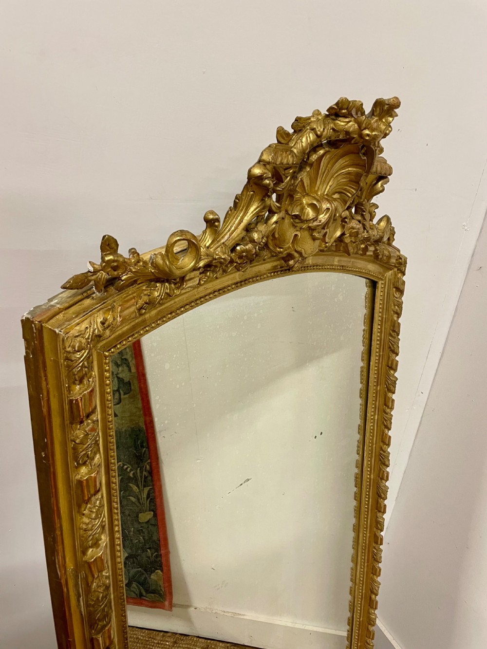 A late nineteenth-century gilded wall mirror featuring an arched top, carved shell cresting, and foliate moulding on the frame. View II