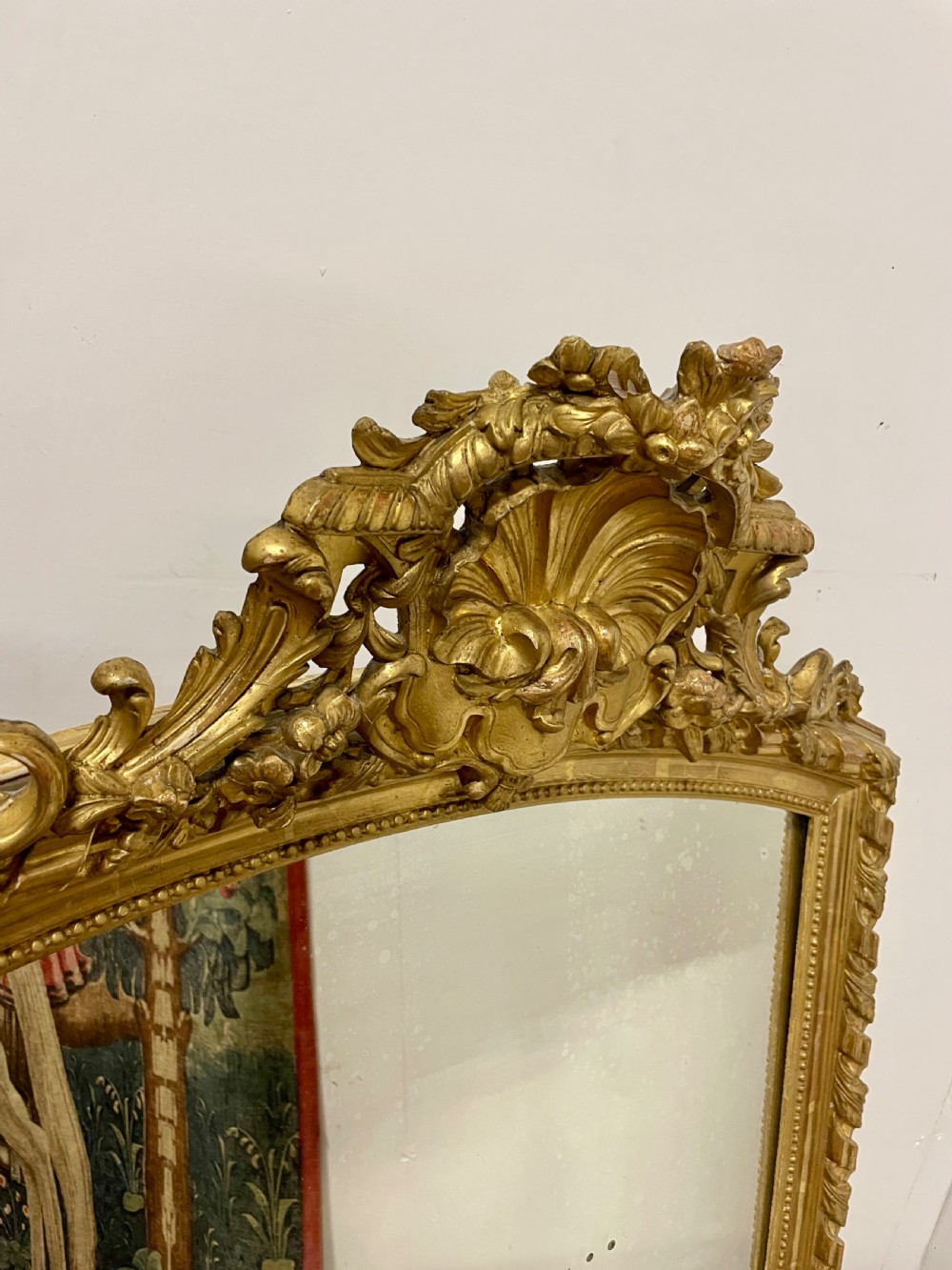 A late nineteenth-century gilded wall mirror featuring an arched top, carved shell cresting, and foliate moulding on the frame. View III