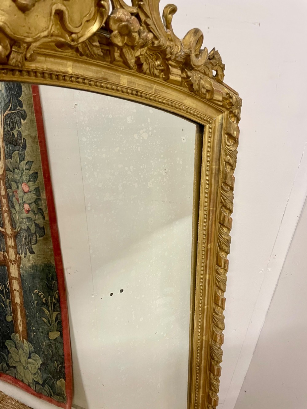 A late nineteenth-century gilded wall mirror featuring an arched top, carved shell cresting, and foliate moulding on the frame. View IV