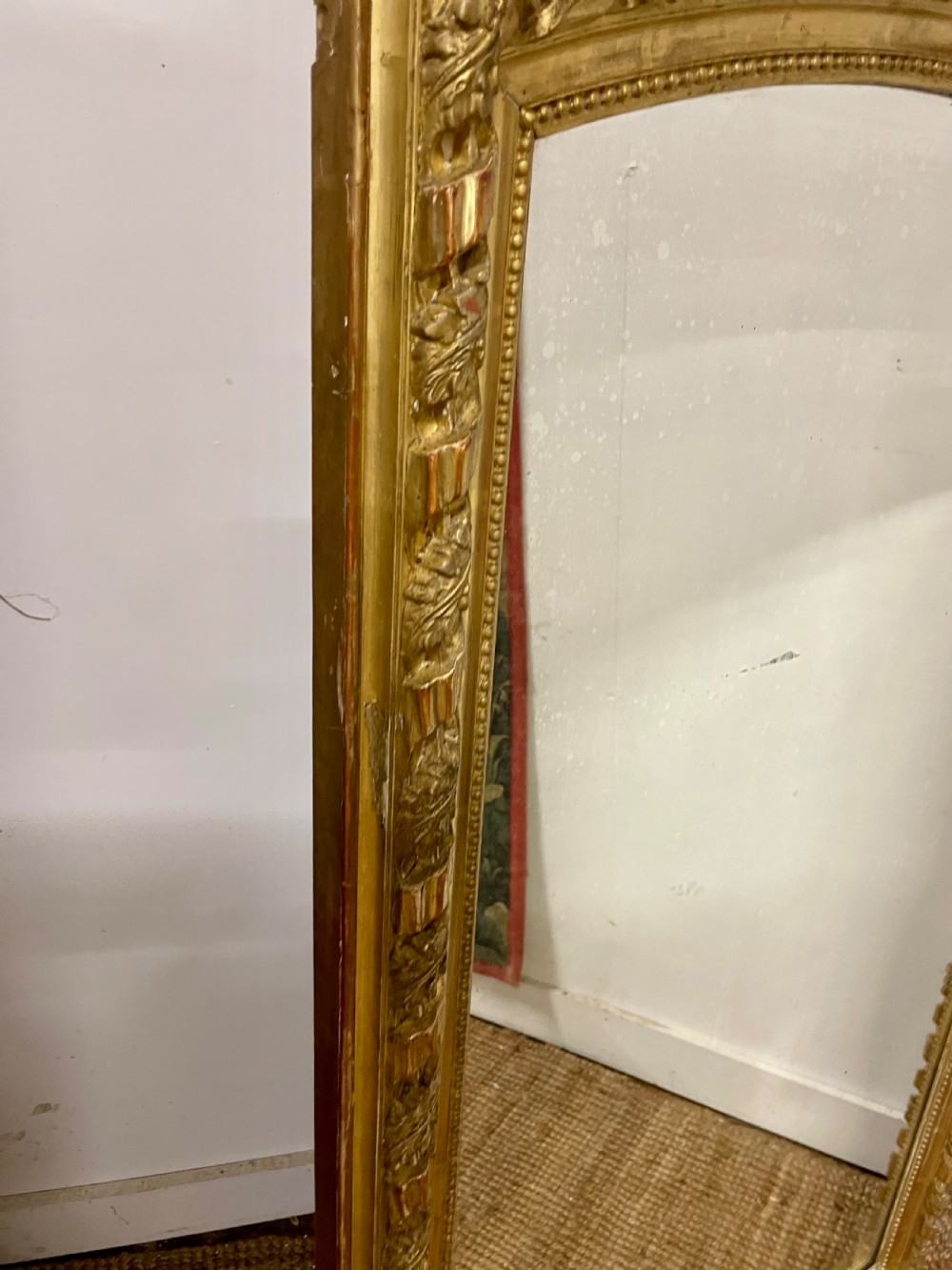 A late nineteenth-century gilded wall mirror featuring an arched top, carved shell cresting, and foliate moulding on the frame. View IX