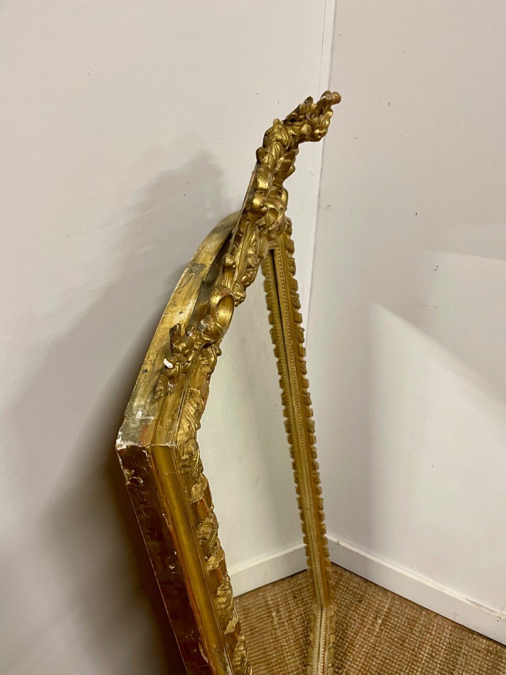 A late nineteenth-century gilded wall mirror featuring an arched top, carved shell cresting, and foliate moulding on the frame. View X