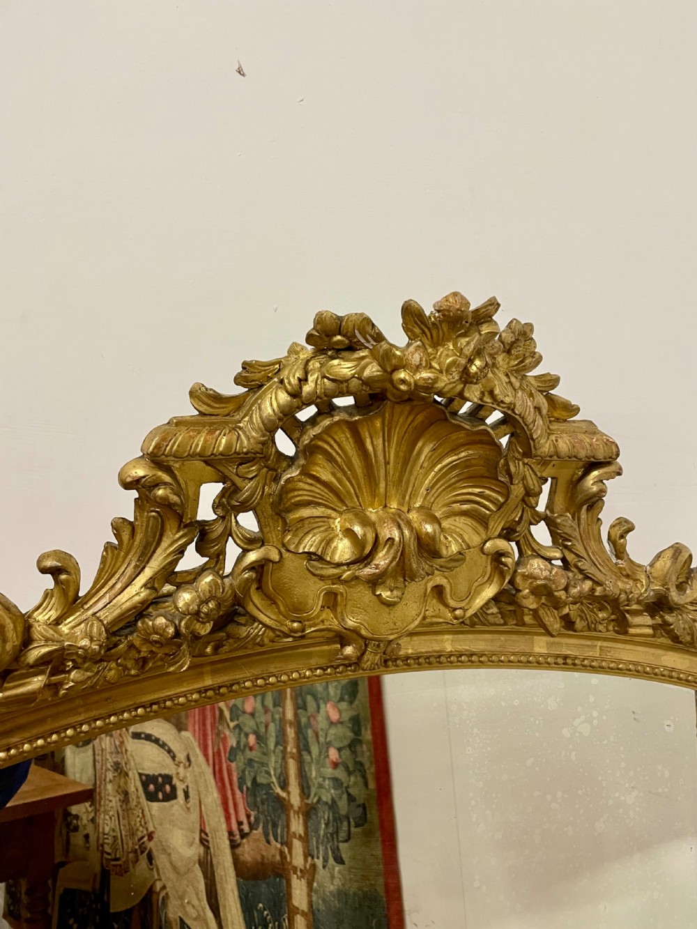 A late nineteenth-century gilded wall mirror featuring an arched top, carved shell cresting, and foliate moulding on the frame. View XI