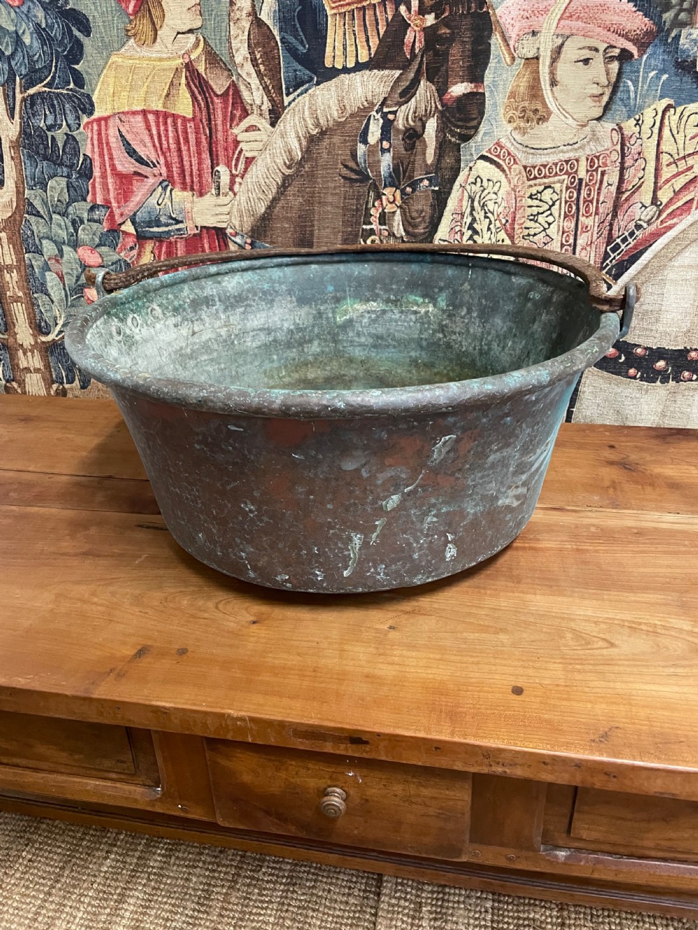 A 19th-century round copper log bin featuring a natural green verdigris patina and a heavy wrought iron swing handle.