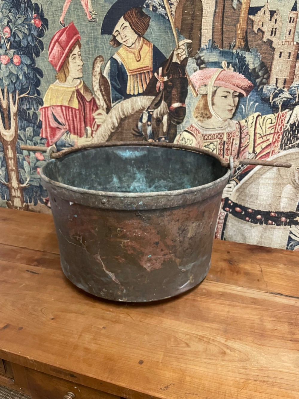 A circular 19th-century copper vessel with a verdigris interior, patinated copper exterior, rolled rim, and wrought iron side handles.