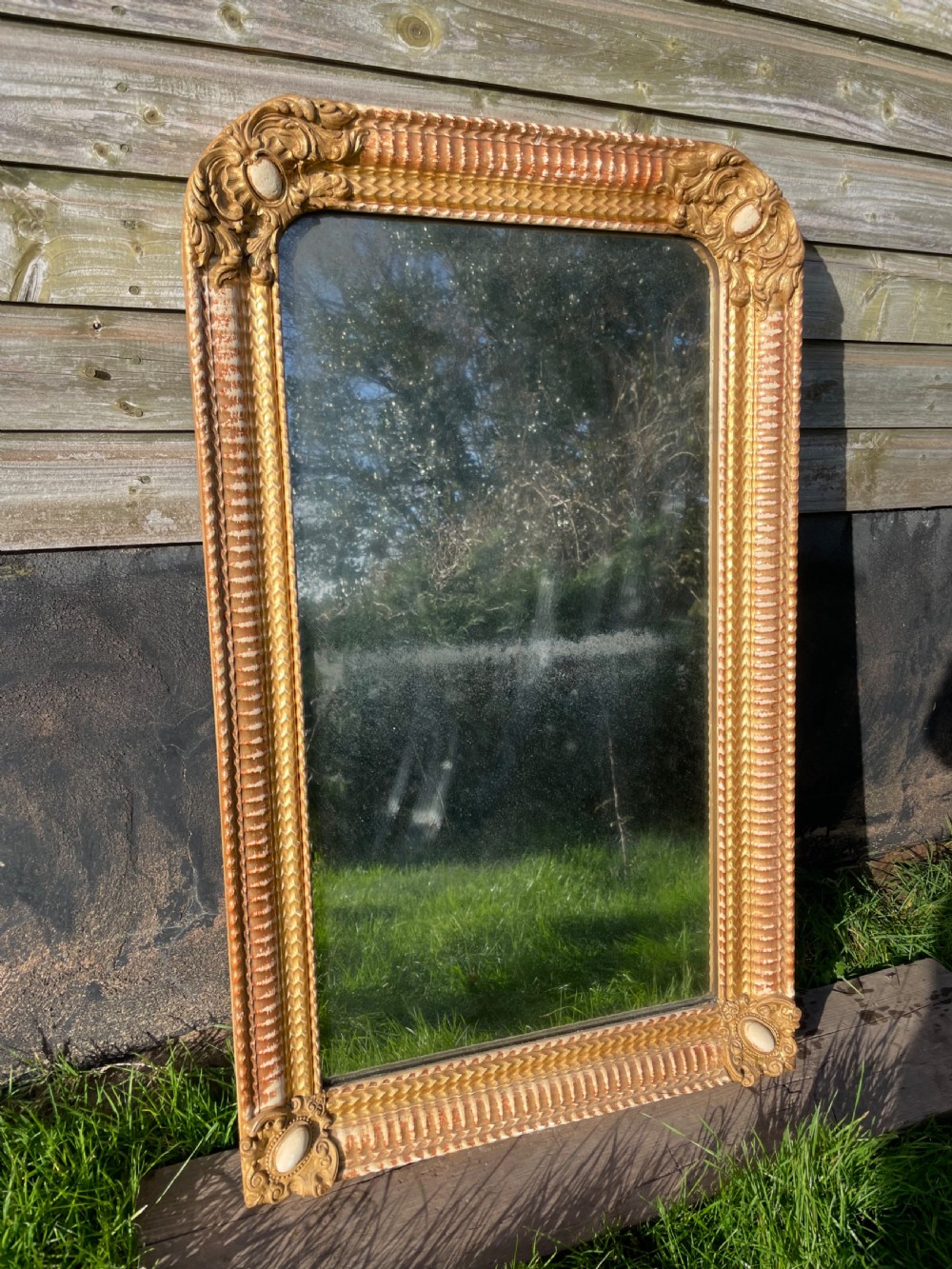 A 19th-century rectangular wall mirror featuring an arched upper frame with detailed giltwood moulding, corner cartouches, and patinated mirror glass.