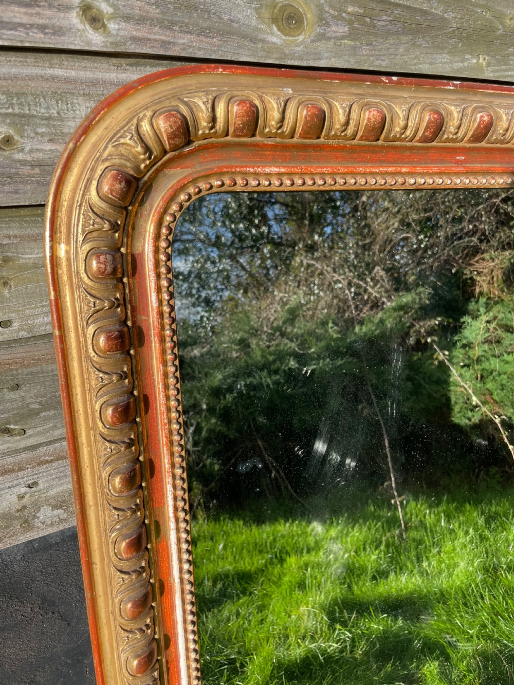 A 19th-century arched top wall mirror featuring a gadrooned and beaded gilt frame with visible red bole underlying the gold leaf. View II