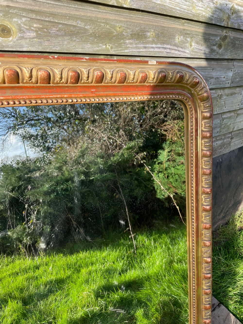 A 19th-century arched top wall mirror featuring a gadrooned and beaded gilt frame with visible red bole underlying the gold leaf. View III
