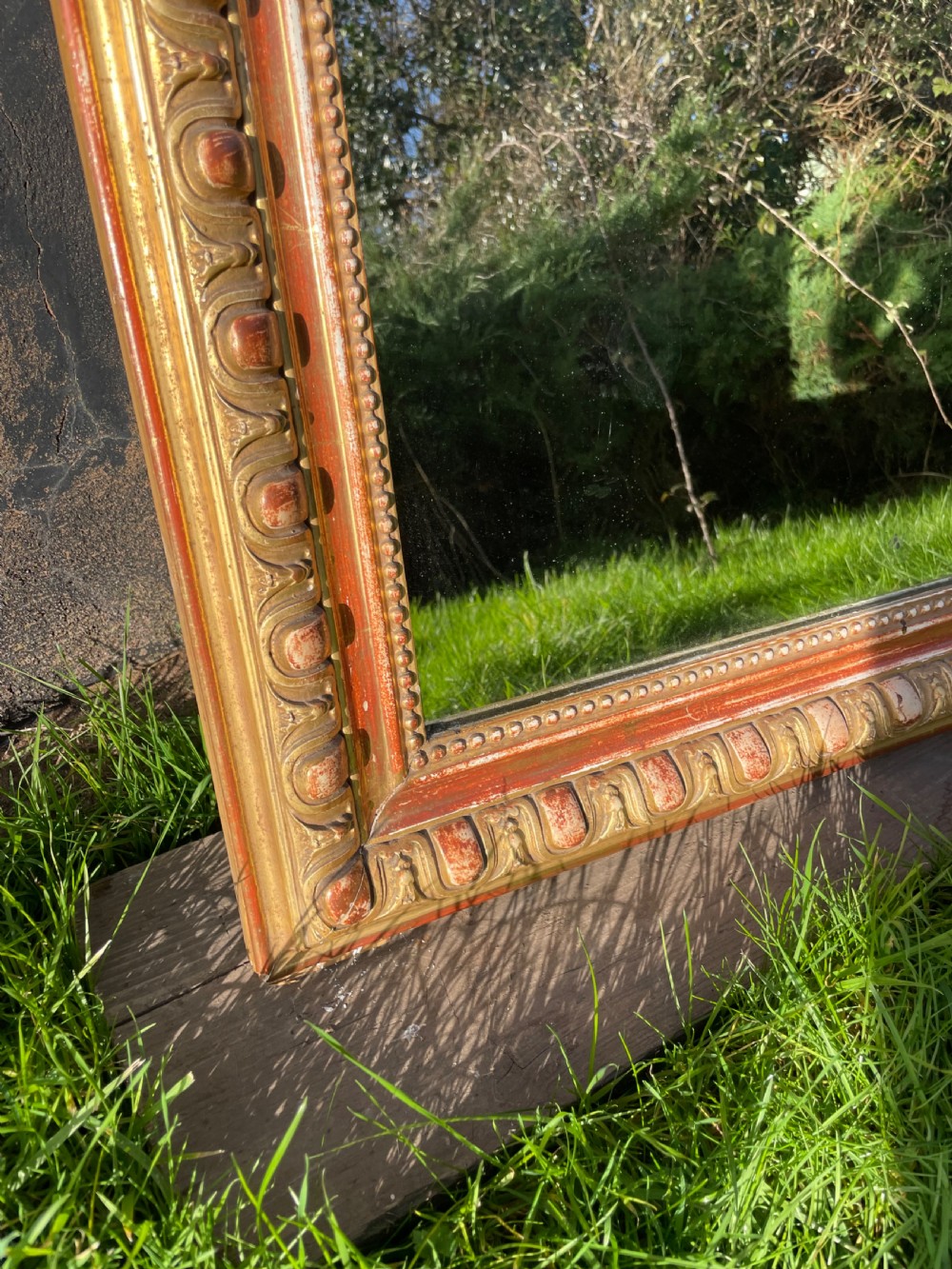 A 19th-century arched top wall mirror featuring a gadrooned and beaded gilt frame with visible red bole underlying the gold leaf. View IV