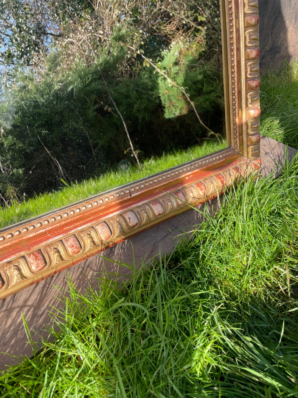 A 19th-century arched top wall mirror featuring a gadrooned and beaded gilt frame with visible red bole underlying the gold leaf. View VI