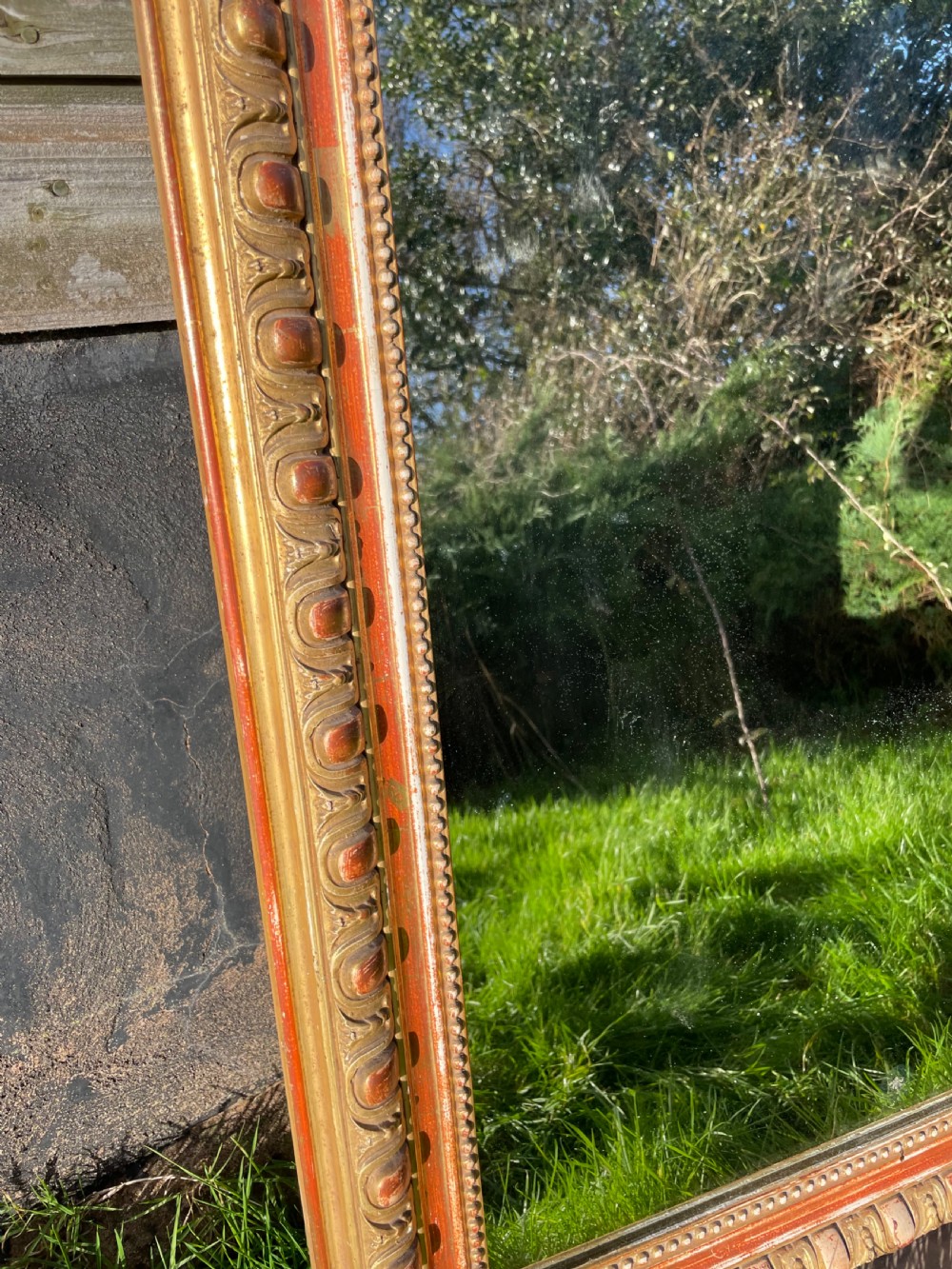 A 19th-century arched top wall mirror featuring a gadrooned and beaded gilt frame with visible red bole underlying the gold leaf. View VII