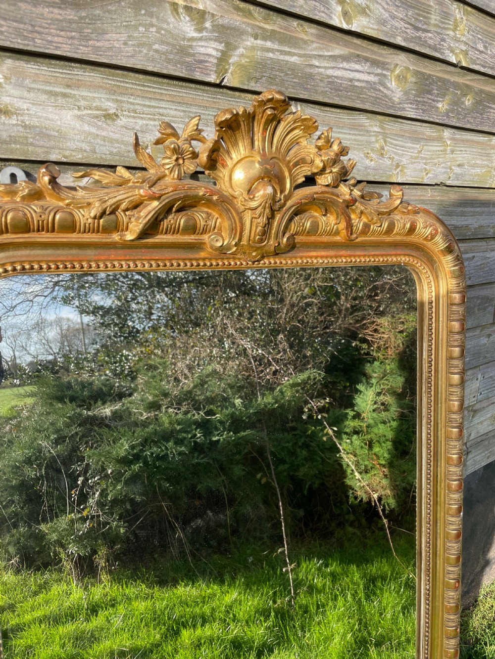 A large 19th-century gilded overmantle mirror featuring an arched top frame adorned with a carved floral shell crest and beaded inner moulding. View II