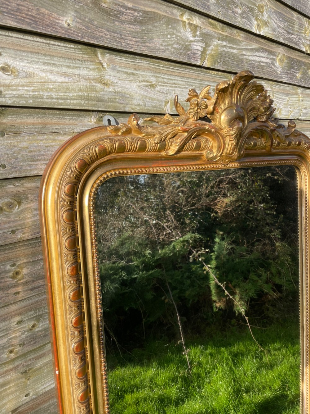 A large 19th-century gilded overmantle mirror featuring an arched top frame adorned with a carved floral shell crest and beaded inner moulding. View III