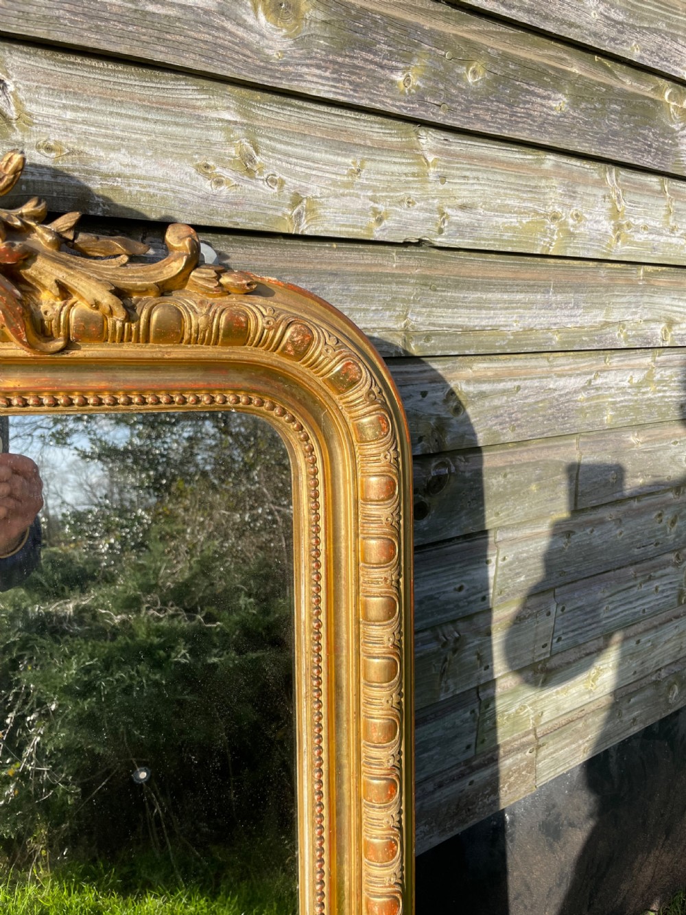 A large 19th-century gilded overmantle mirror featuring an arched top frame adorned with a carved floral shell crest and beaded inner moulding. View X