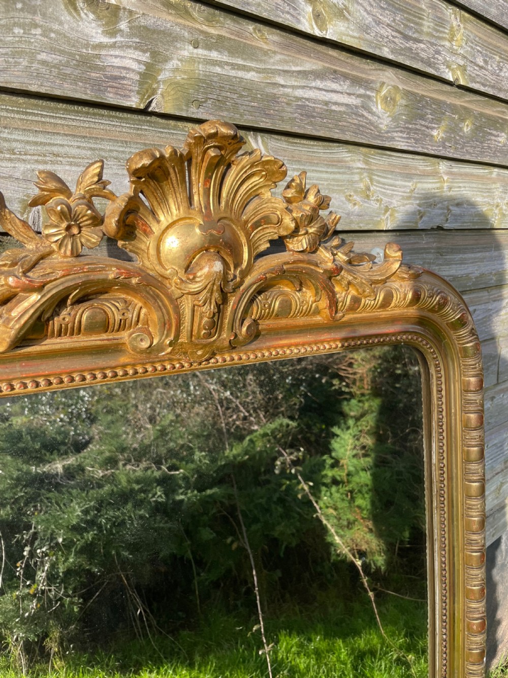 A large 19th-century gilded overmantle mirror featuring an arched top frame adorned with a carved floral shell crest and beaded inner moulding. View XI