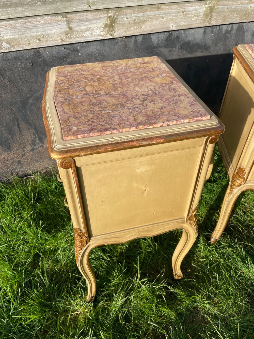 A pair of early 20th century French style cream painted and gilded bedside cabinets featuring fitted marble tops, three drawers, and carved cabriole legs. View VIII