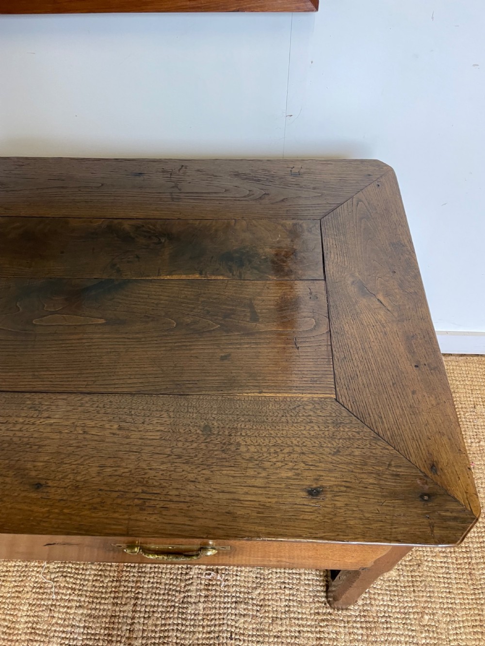 An antique chestnut dresser base features a rectangular wooden top, three horizontal drawers with brass drop handles, and straight legs connected by stretchers. View VI