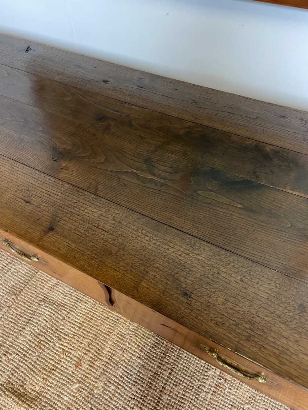 An antique chestnut dresser base features a rectangular wooden top, three horizontal drawers with brass drop handles, and straight legs connected by stretchers. View VII