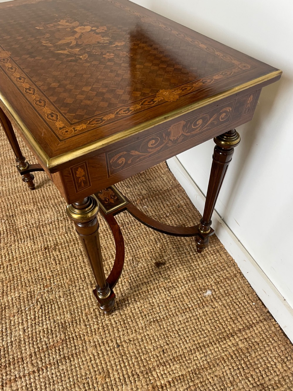 An overhead view of a French Napoleon III wooden side table featuring intricate floral marquetry on the top, slender turned legs, and brass edging. View IV