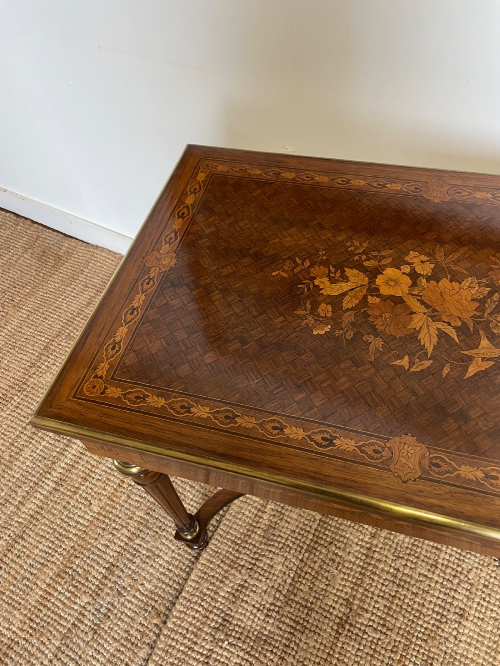 An overhead view of a French Napoleon III wooden side table featuring intricate floral marquetry on the top, slender turned legs, and brass edging. View VII