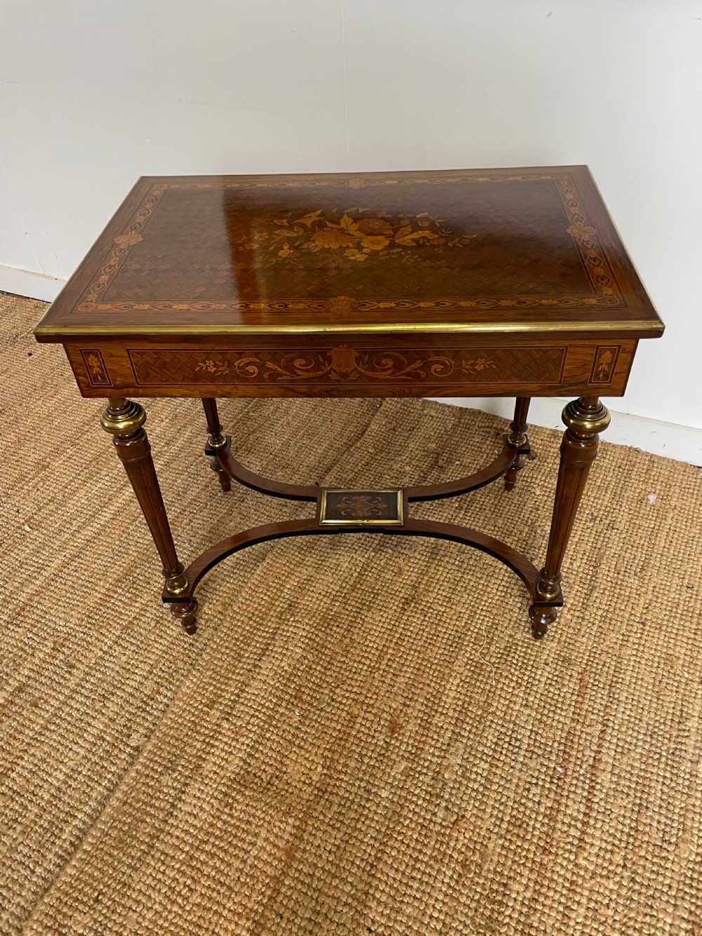 An overhead view of a French Napoleon III wooden side table featuring intricate floral marquetry on the top, slender turned legs, and brass edging. View VIII