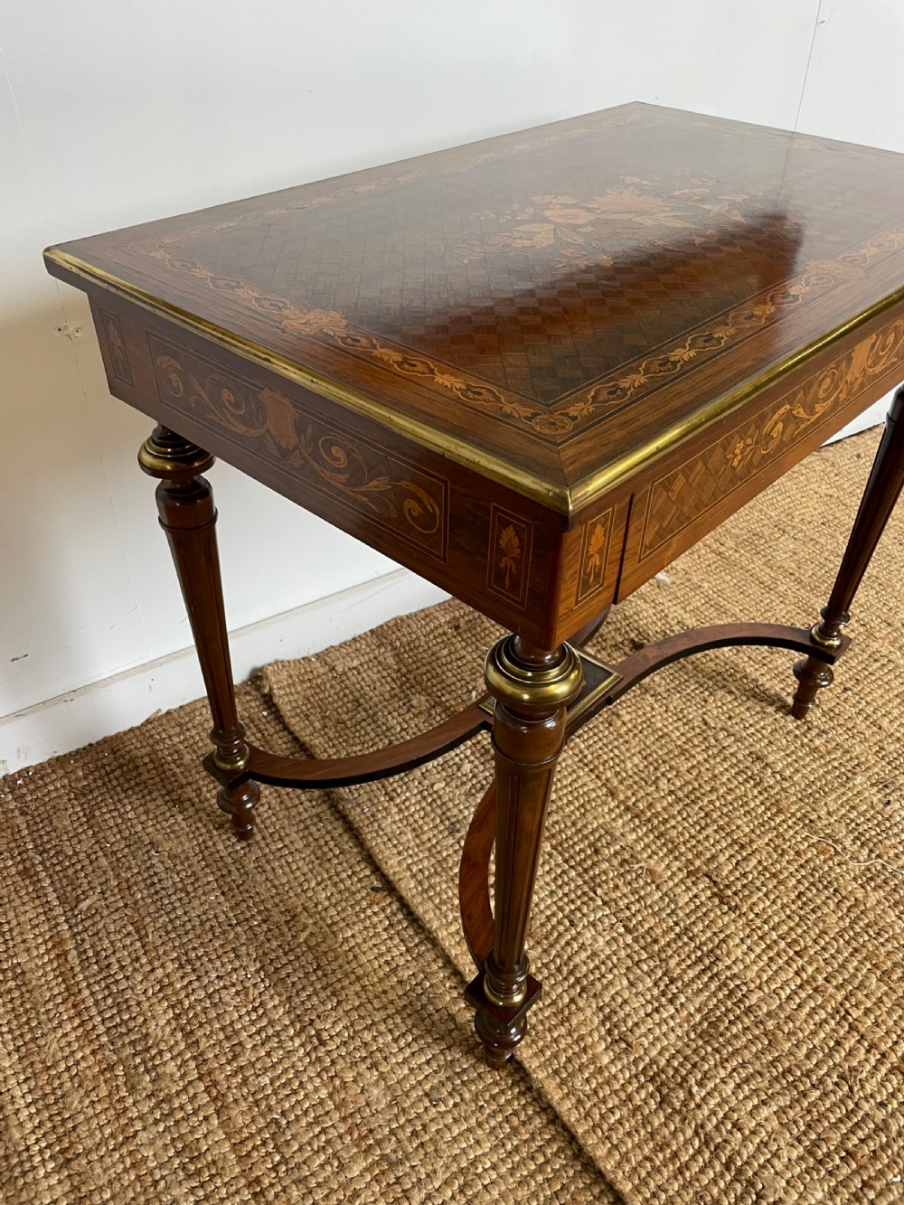 An overhead view of a French Napoleon III wooden side table featuring intricate floral marquetry on the top, slender turned legs, and brass edging. View XI