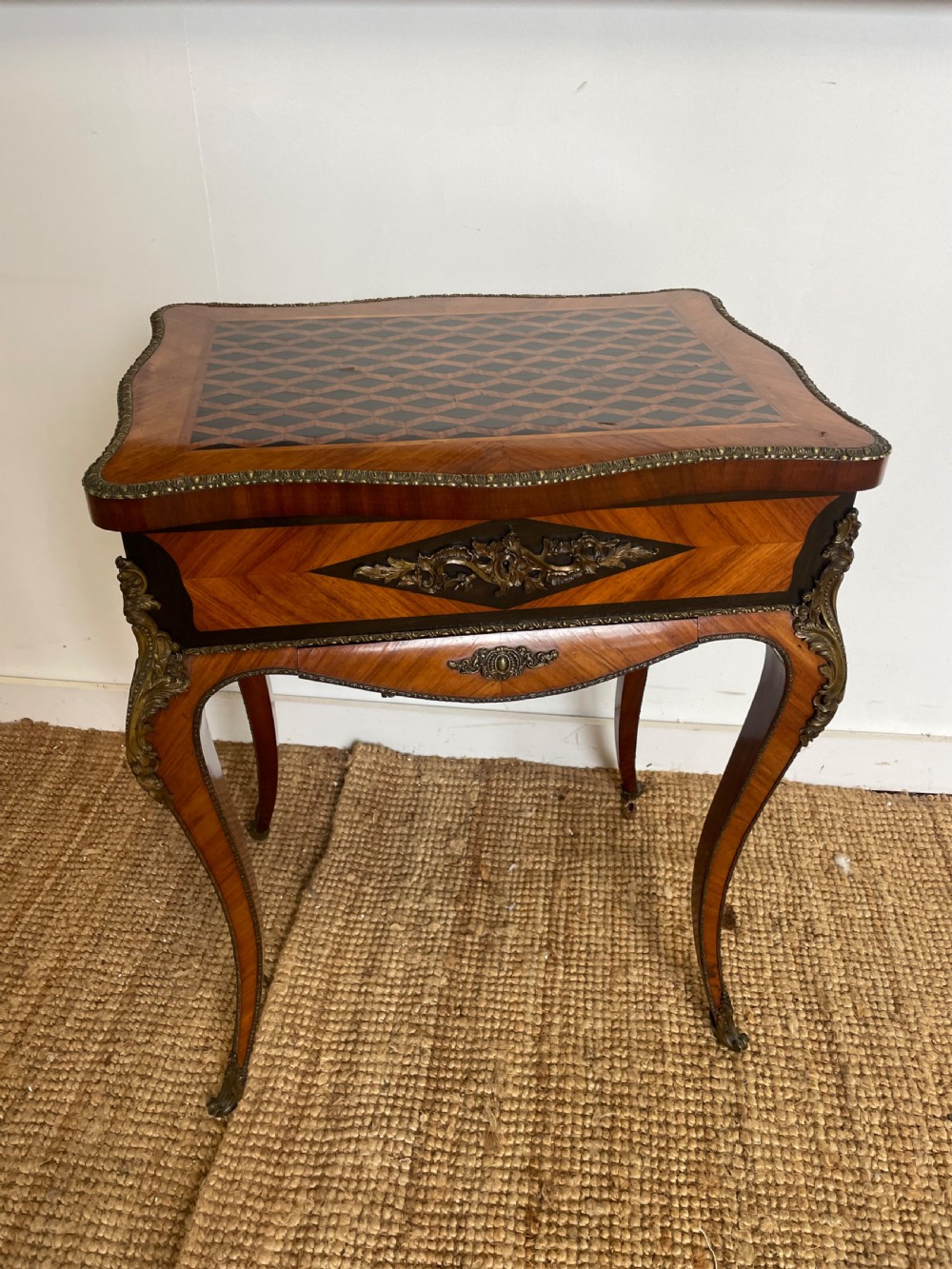 A 19th-century French Napoleon III kingwood worktable featuring parquetry top surface, serpentine cabriole legs, and cast brass mounts.