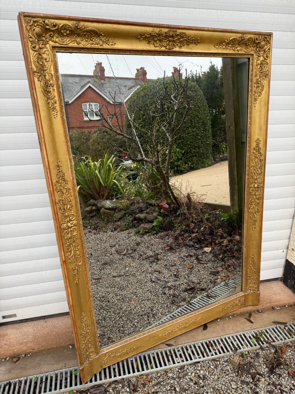 A large rectangular early 19th-century Empire style overmantel mirror featuring a gilded frame with ornate floral moulding.