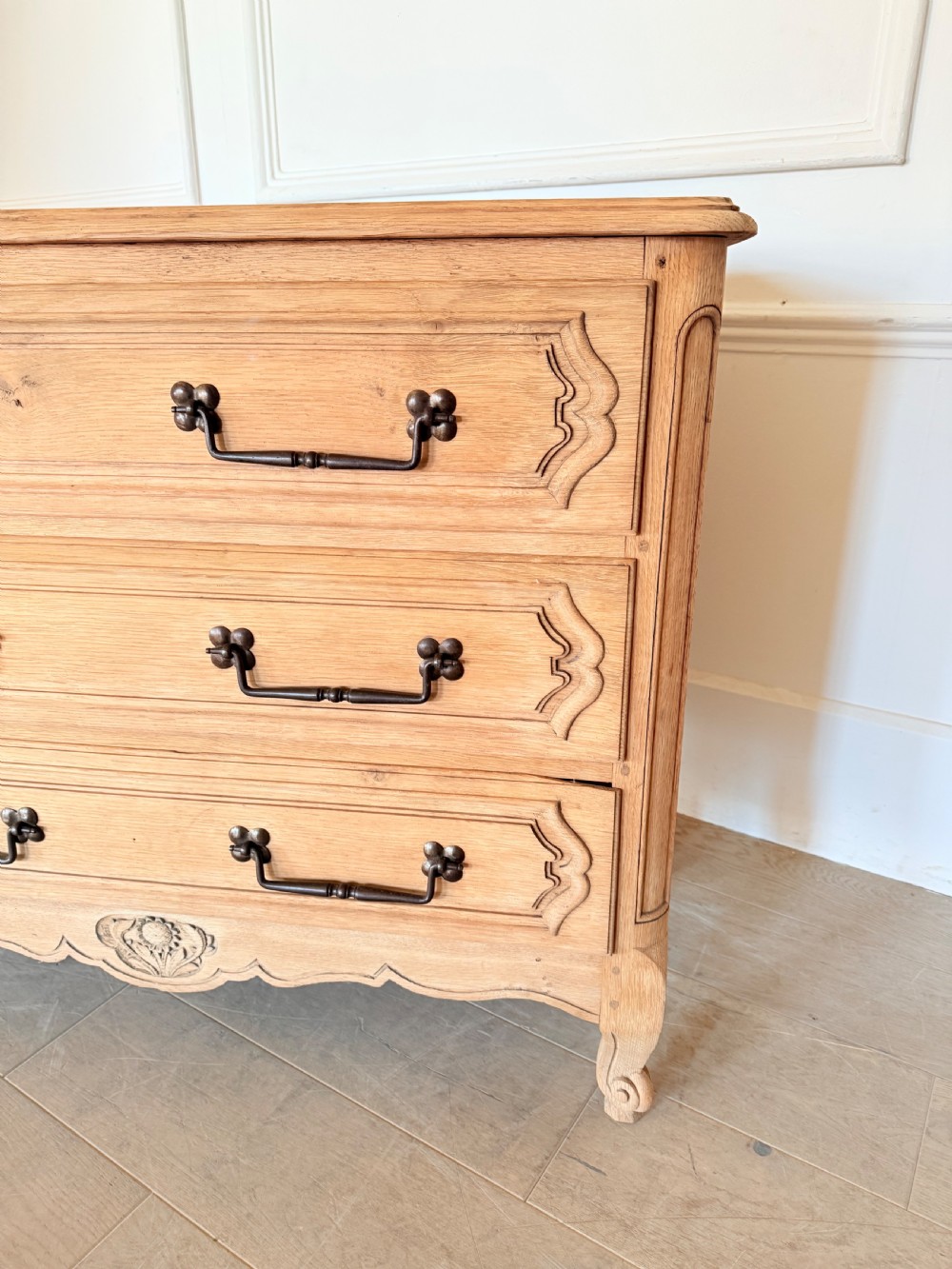A scrubbed light oak commode chest featuring three long drawers with moulded panel detailing, iron drop handles, carved lower apron, and cabriole feet. View III