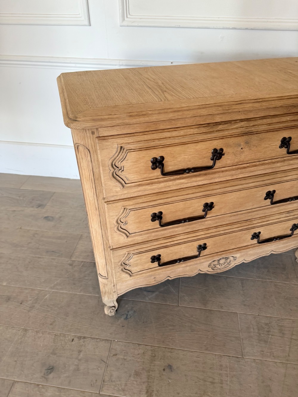 A scrubbed light oak commode chest featuring three long drawers with moulded panel detailing, iron drop handles, carved lower apron, and cabriole feet. View VII