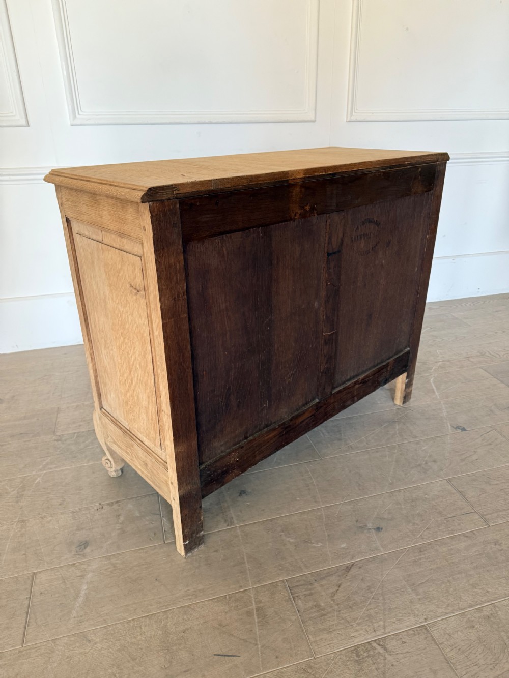 A scrubbed light oak commode chest featuring three long drawers with moulded panel detailing, iron drop handles, carved lower apron, and cabriole feet. View IX