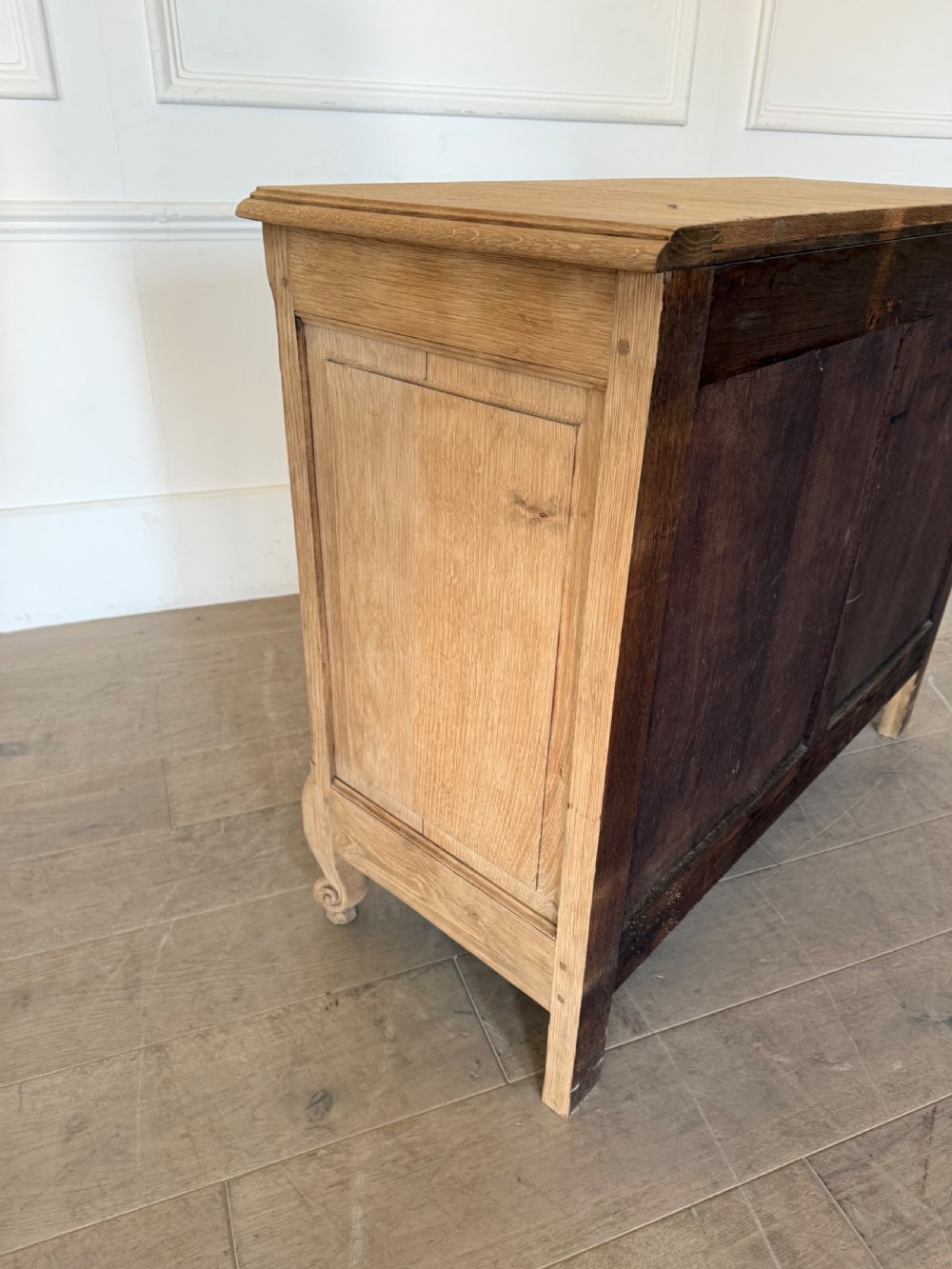A scrubbed light oak commode chest featuring three long drawers with moulded panel detailing, iron drop handles, carved lower apron, and cabriole feet. View X