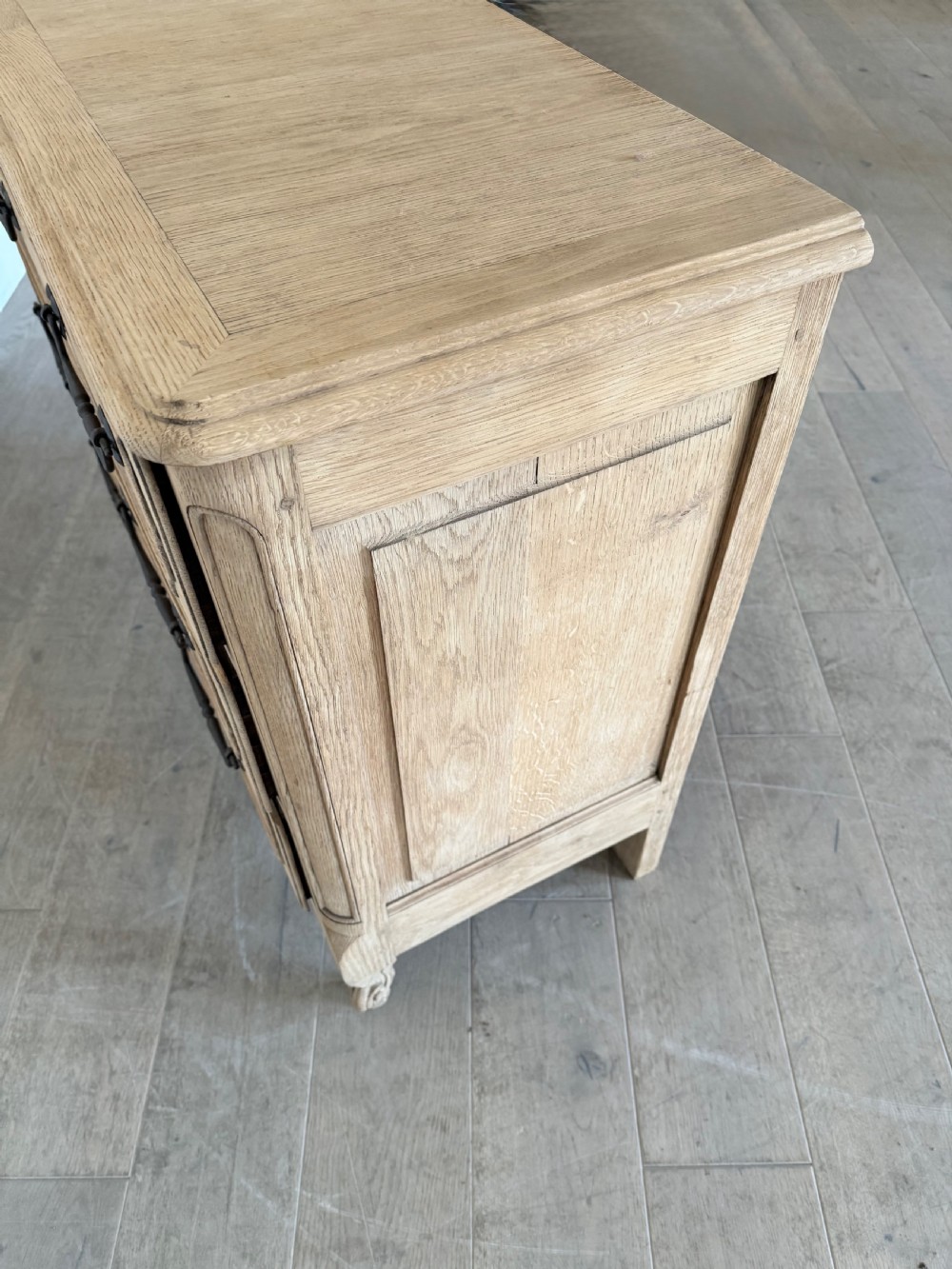 A scrubbed light oak commode chest featuring three long drawers with moulded panel detailing, iron drop handles, carved lower apron, and cabriole feet. View XII