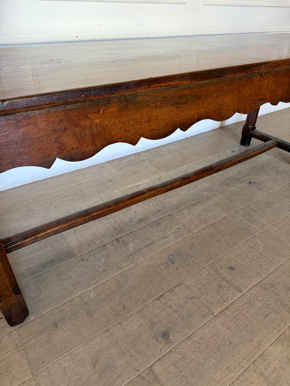 An eighteenth century oak console table with a rectangular plank top and a shaped frieze above plain stretcher-joined legs. View IV