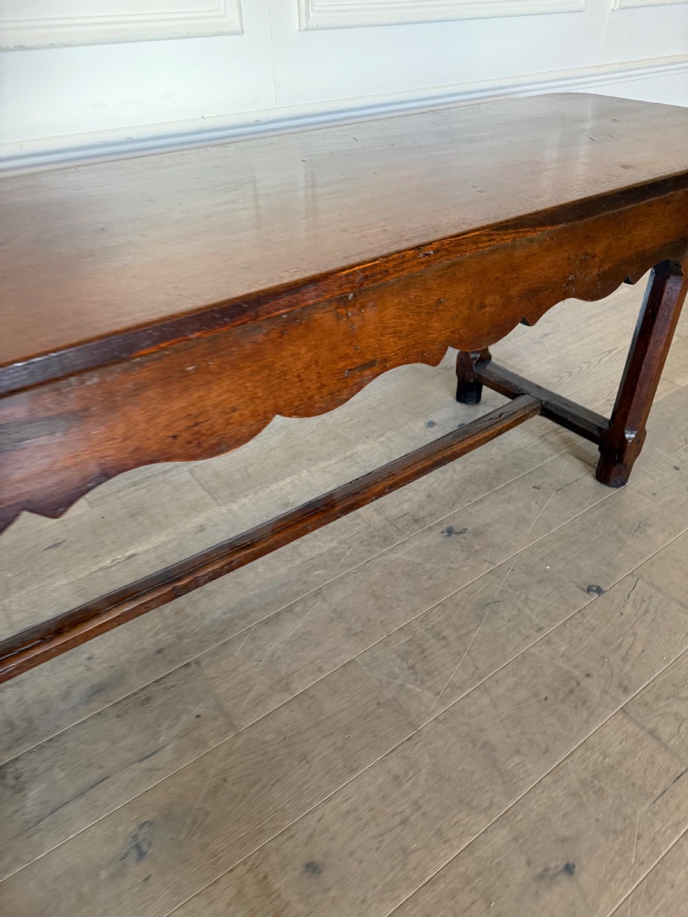 An eighteenth century oak console table with a rectangular plank top and a shaped frieze above plain stretcher-joined legs. View V