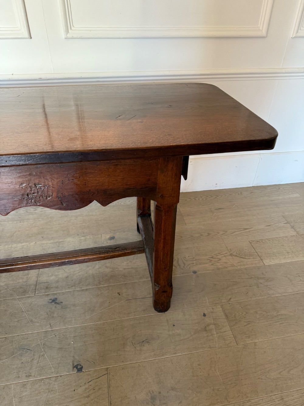 An eighteenth century oak console table with a rectangular plank top and a shaped frieze above plain stretcher-joined legs. View VI