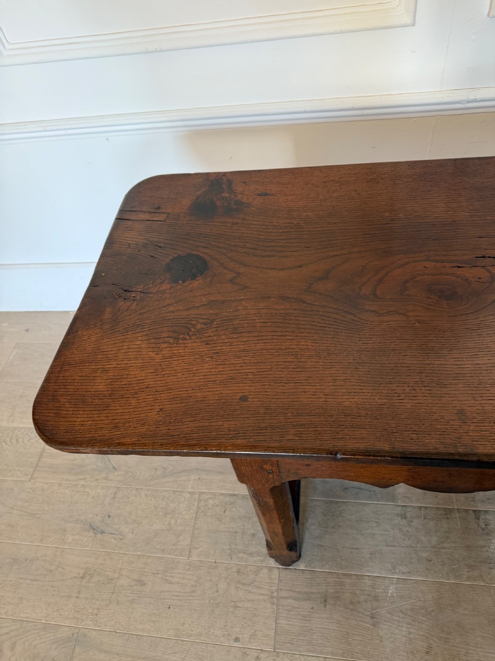 An eighteenth century oak console table with a rectangular plank top and a shaped frieze above plain stretcher-joined legs. View VIII