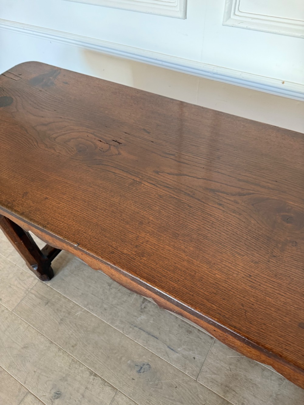 An eighteenth century oak console table with a rectangular plank top and a shaped frieze above plain stretcher-joined legs. View IX