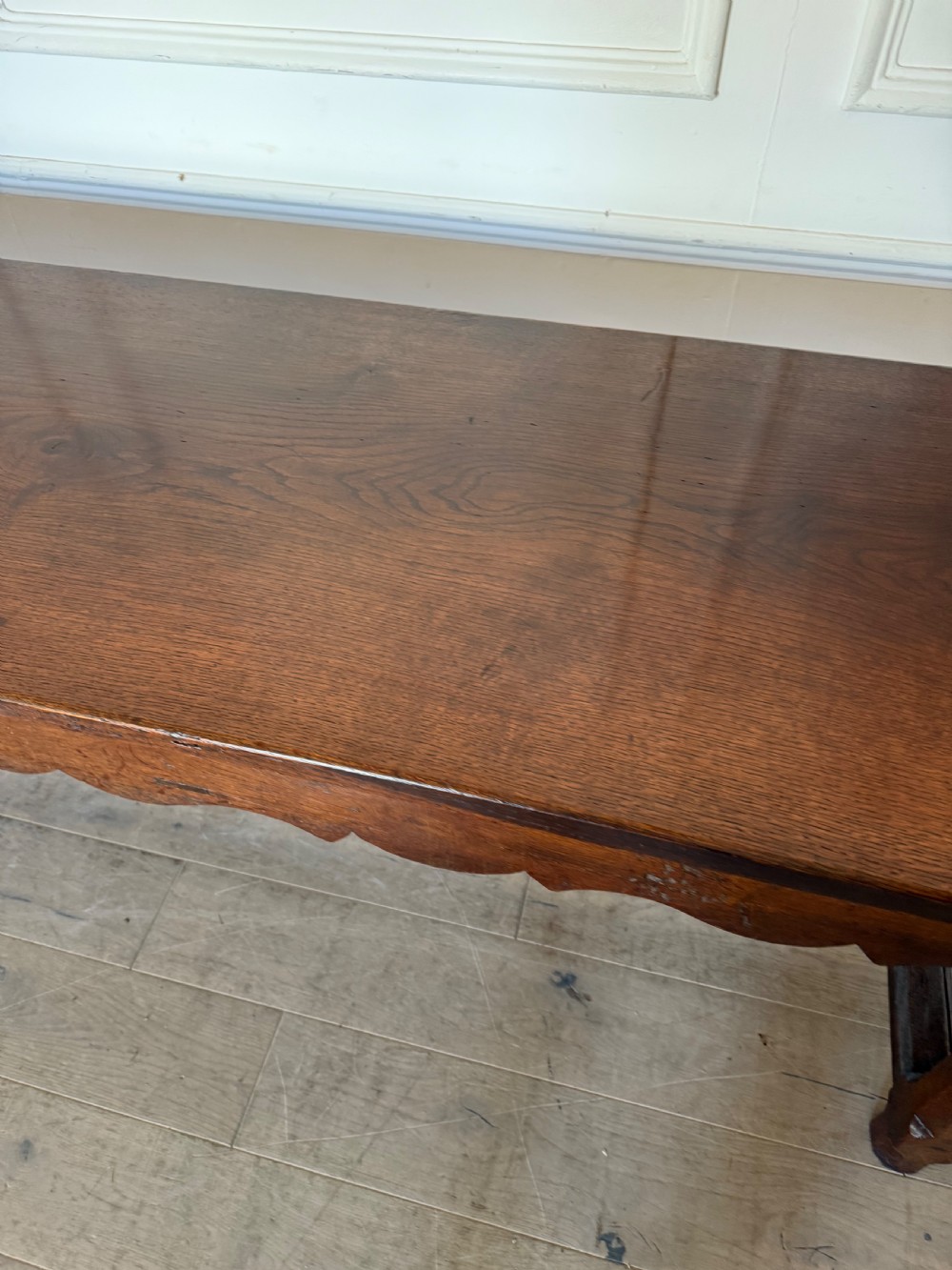 An eighteenth century oak console table with a rectangular plank top and a shaped frieze above plain stretcher-joined legs. View X