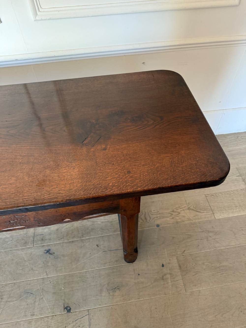 An eighteenth century oak console table with a rectangular plank top and a shaped frieze above plain stretcher-joined legs. View XI