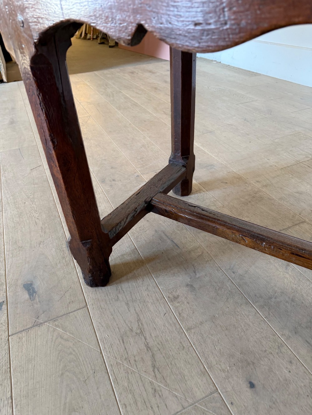 An eighteenth century oak console table with a rectangular plank top and a shaped frieze above plain stretcher-joined legs. View XVII