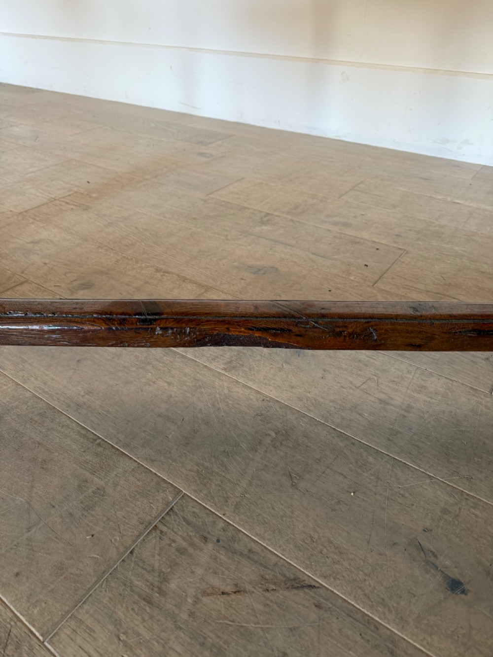 An eighteenth century oak console table with a rectangular plank top and a shaped frieze above plain stretcher-joined legs. View XVIII