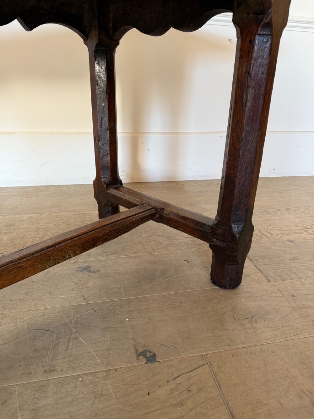 An eighteenth century oak console table with a rectangular plank top and a shaped frieze above plain stretcher-joined legs. View XIX