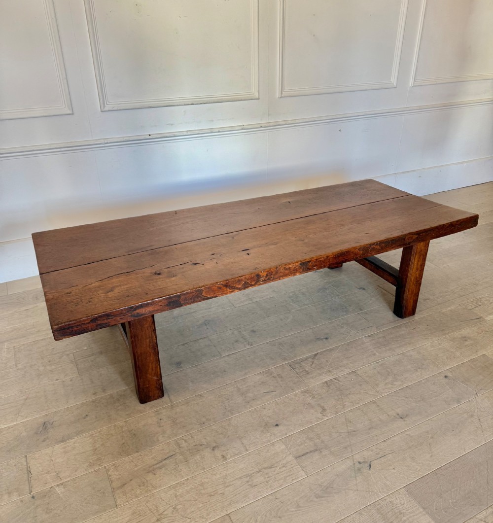 A large rectangular 19th-century elm coffee table with a two-plank top and sturdy wooden legs.