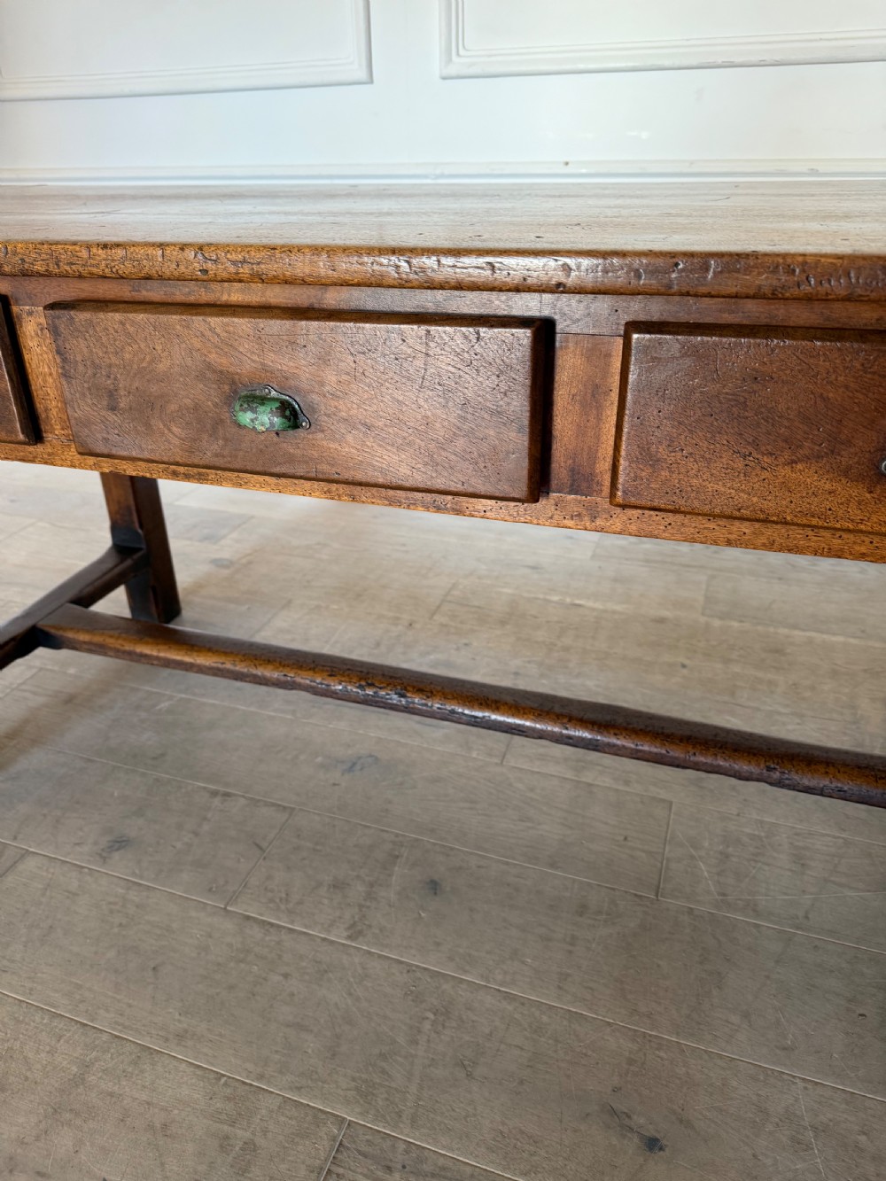 A rectangular 19th-century walnut drapers table featuring a plank top, three drawers with metal drop handles, and an H-stretcher base. View VI